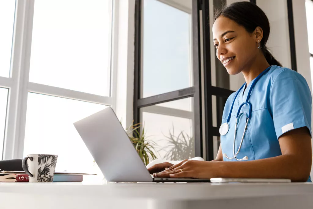 doctor working with laptop while sitting at table in home